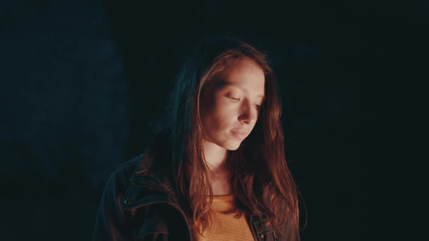 Light shines on face of woman standing in darkness