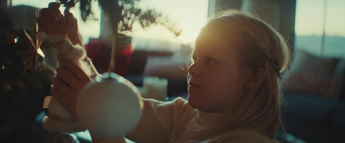 A young girl decorates a christmas tree at home