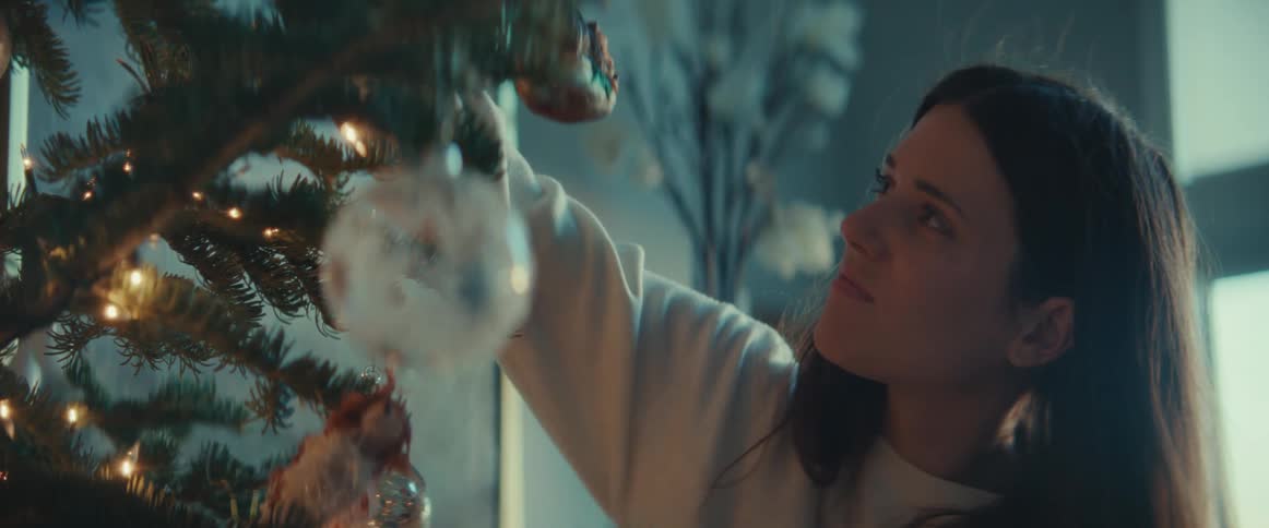 A woman is decorating a christmas tree