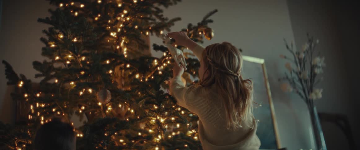 Family decorates christmas tree standing near wall