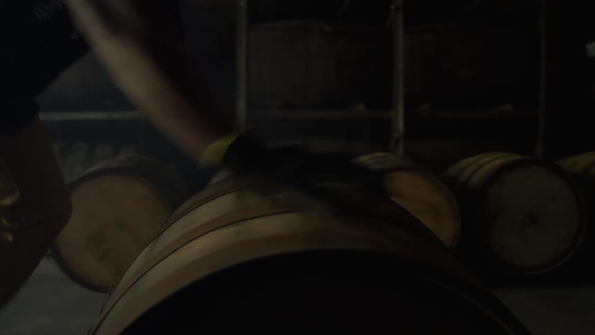 A man pushes a barrel through the warehouse