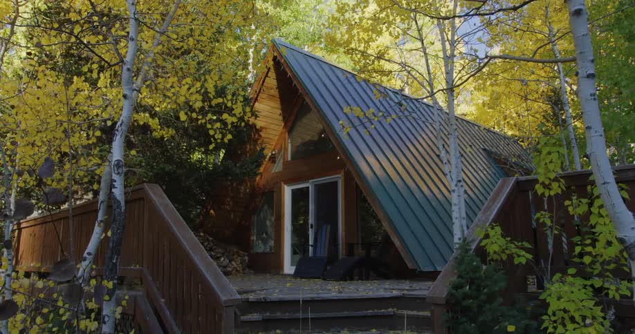 Blue roofed a frame home sits nestled among autumn woods