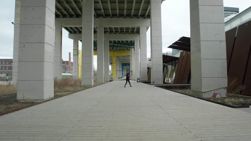 A man is outside shadow boxing under a bridge