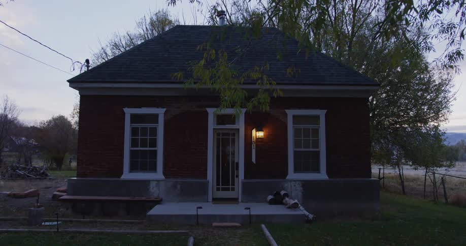 The porch light of a small house is on next to the front door