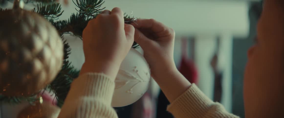 A girl hangs an ornament on her familys christmas tree