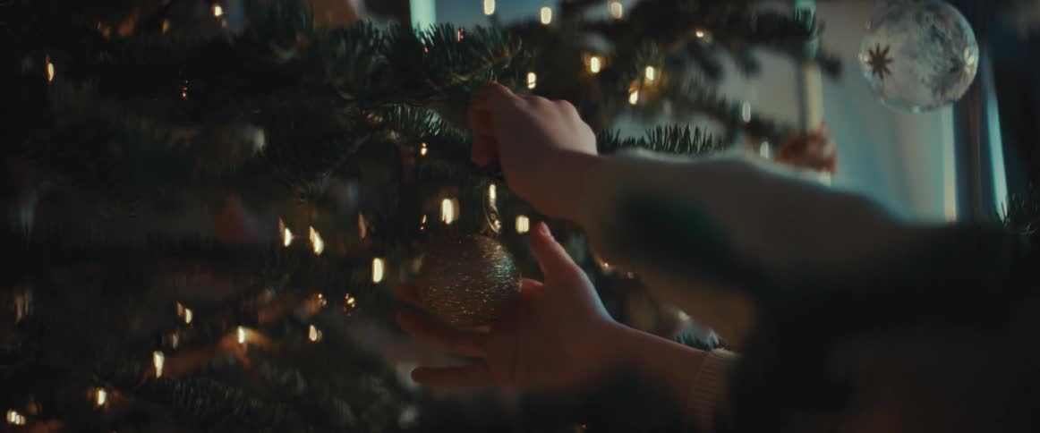 A little boy is hanging decorations on a christmas tree