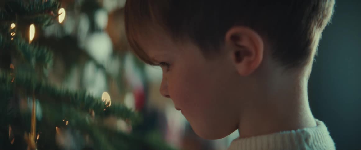 Boy with sweater decorates christmas tree