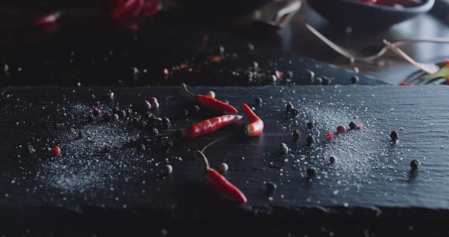 Light shines upon hot chili peppers on a table with berries and powder
