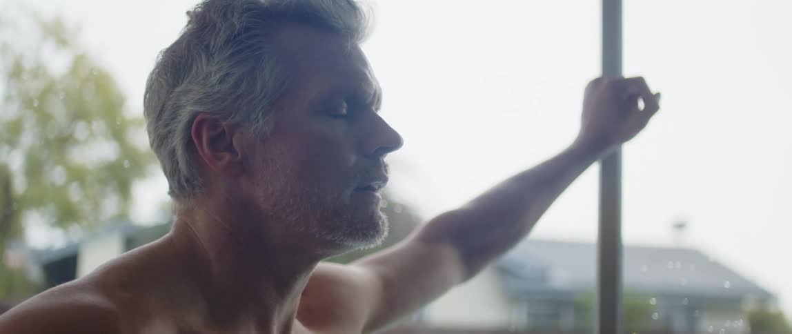 Side profile of muscular man with gray hair breathes heavily after work out