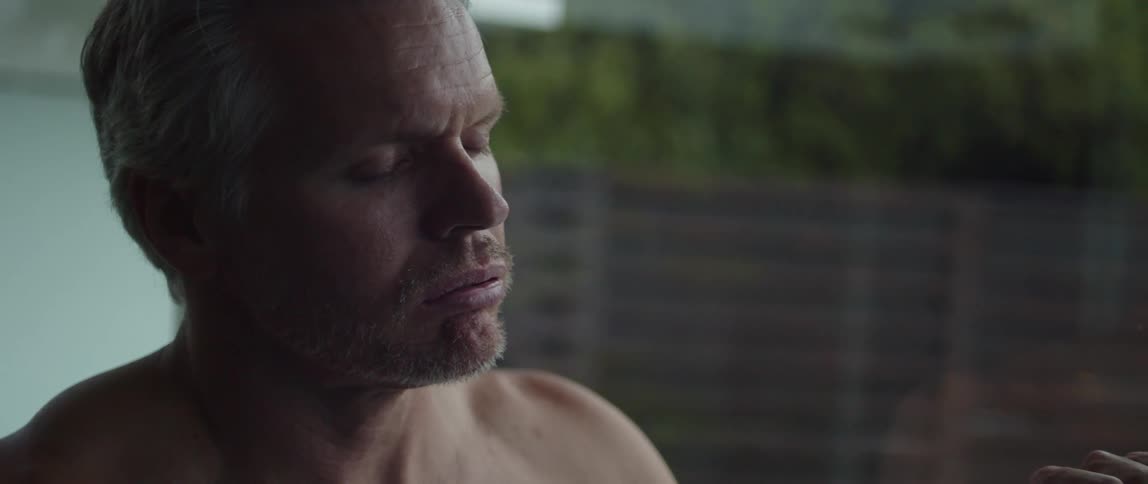 Side profile of muscular topless man breathing and opening eyes