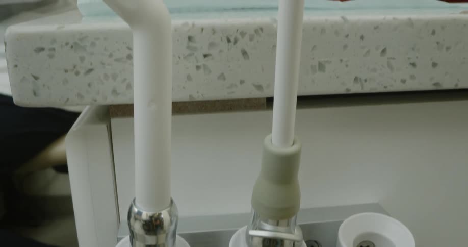 A dental assistant places a suction tool back into its holder