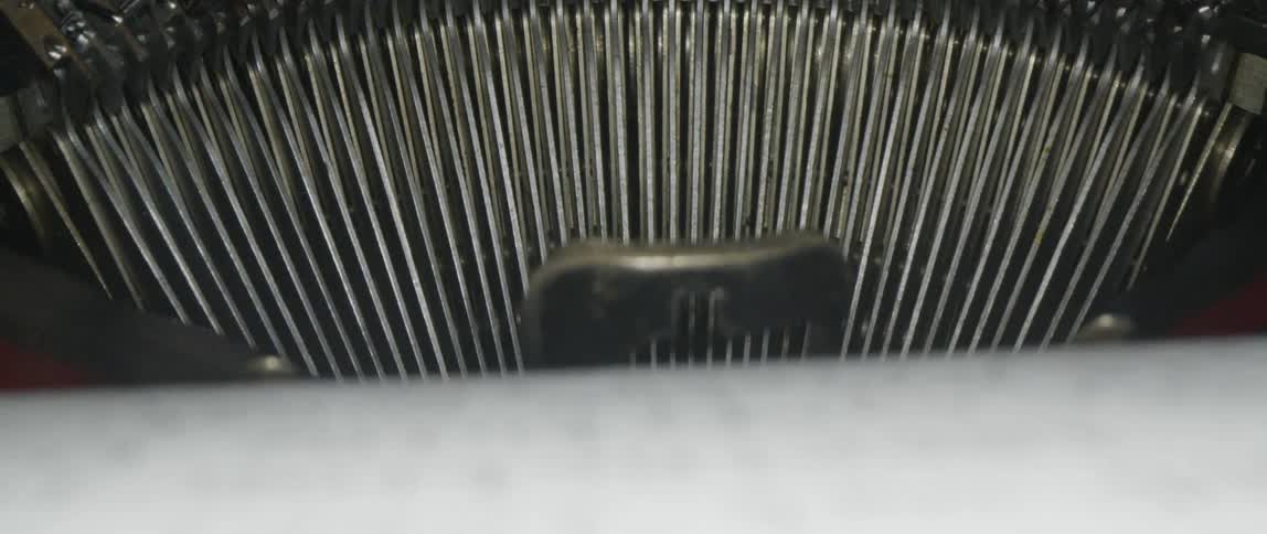 A close up shows both the mechanical parts of a typewriter and the typewritten page in it