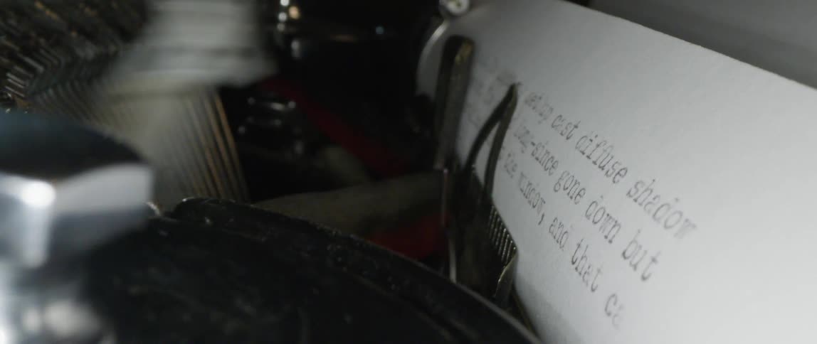 The type bars of a typewriter print text on a sheet of paper
