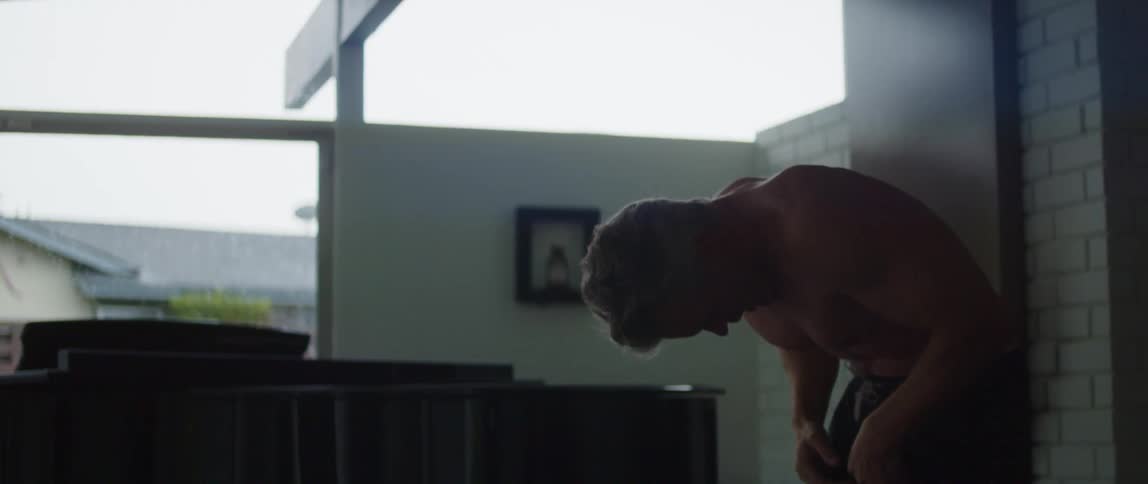 Muscular topless man works out next to grand piano in room