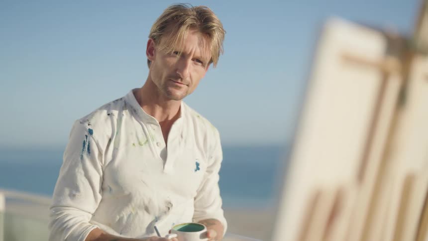 A painter steps back to check his work on the beach