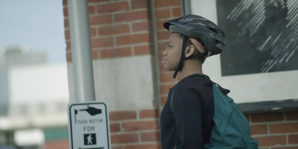 A woman rides her bike up to a crosswalk