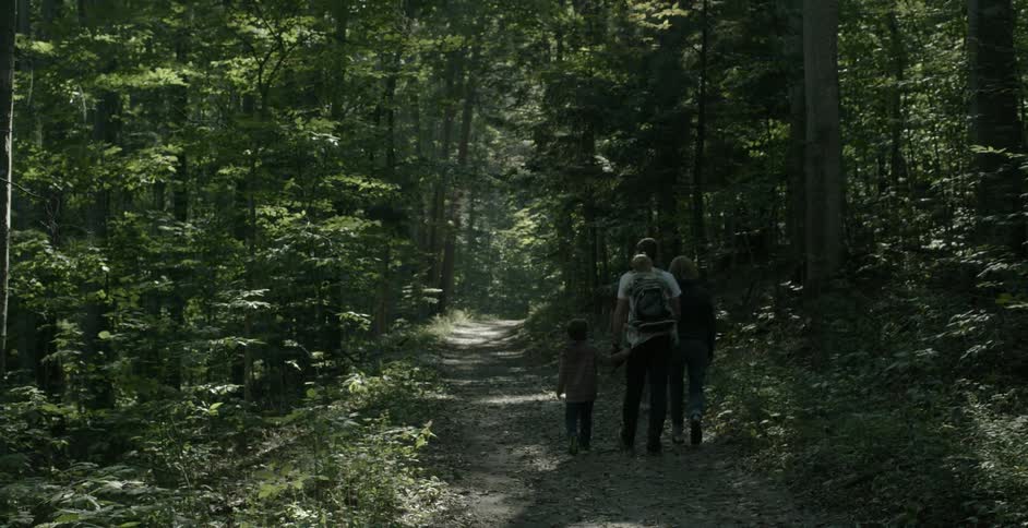 A family walks a wooded trail
