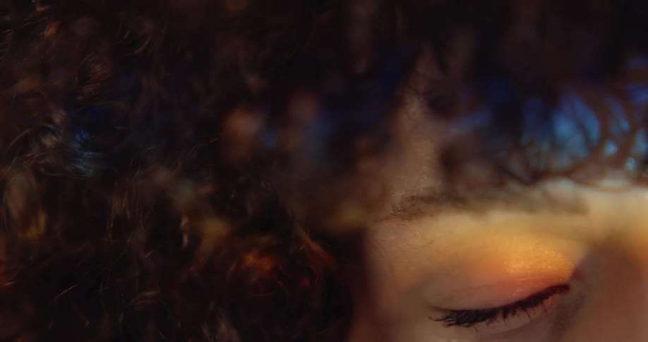 A curly haired woman opens her eyes