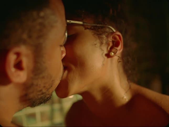 Woman with curly hair glasses and earrings makes out with man with beard