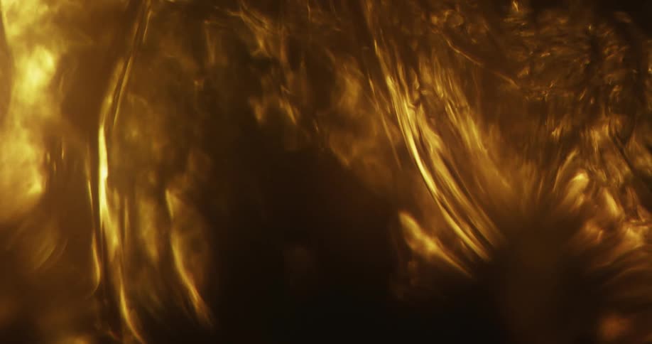 Golden liquid flowing and swirling against shadows of black