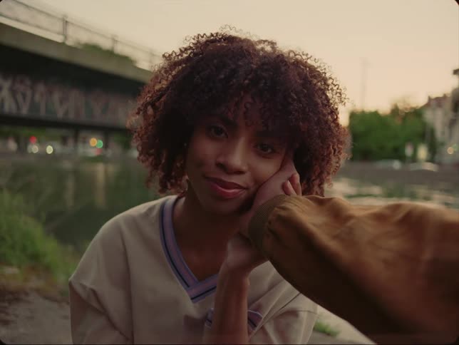 A man reaches his hand out and places it on the cheek of his female companion