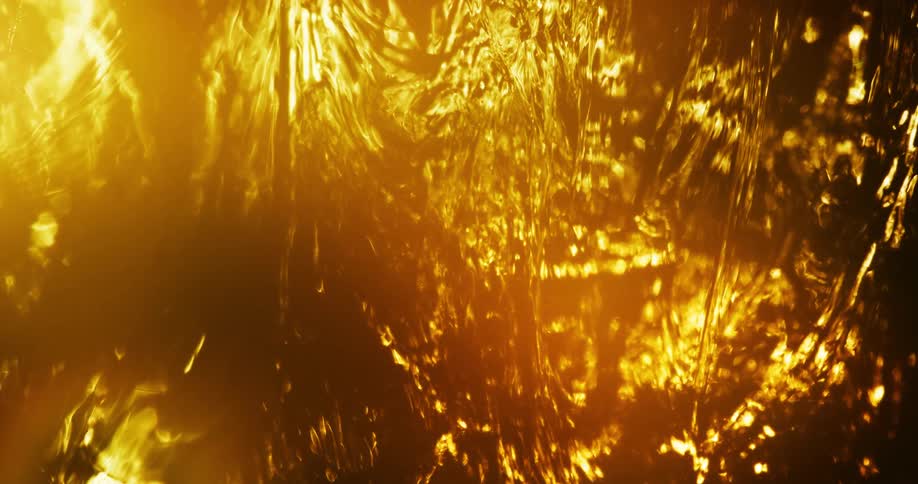 A slow moving fluid is illuminated by a bright orange light making it appear like a flame