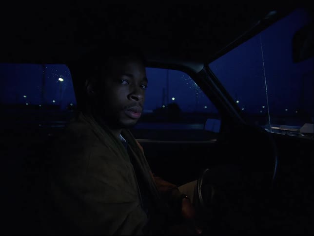 A black male sitting in a vehicle at night