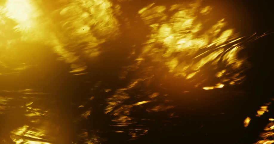 Amber fluid glowing brightly flows slowly as light and shadow play across the surface