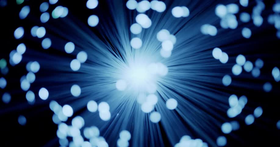 Blue lit filament expands gyrating against a black background