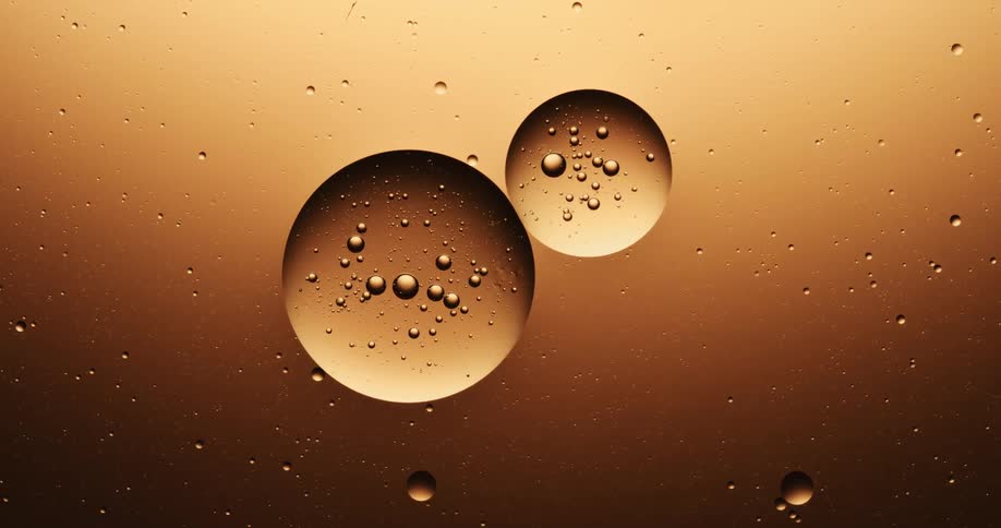 A large bubble in an amber liquid separates into two bubbles