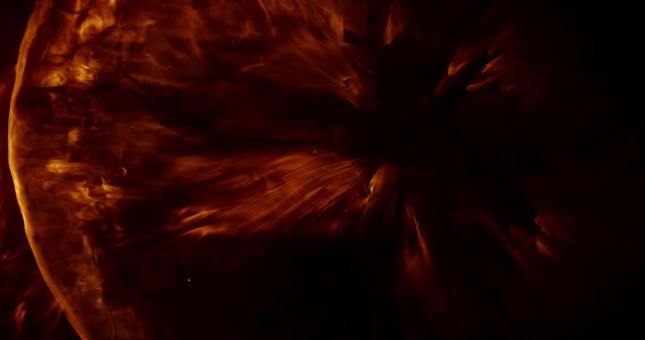 Liquids flow and mix while illuminated by orange light in such a way that it looks like flames