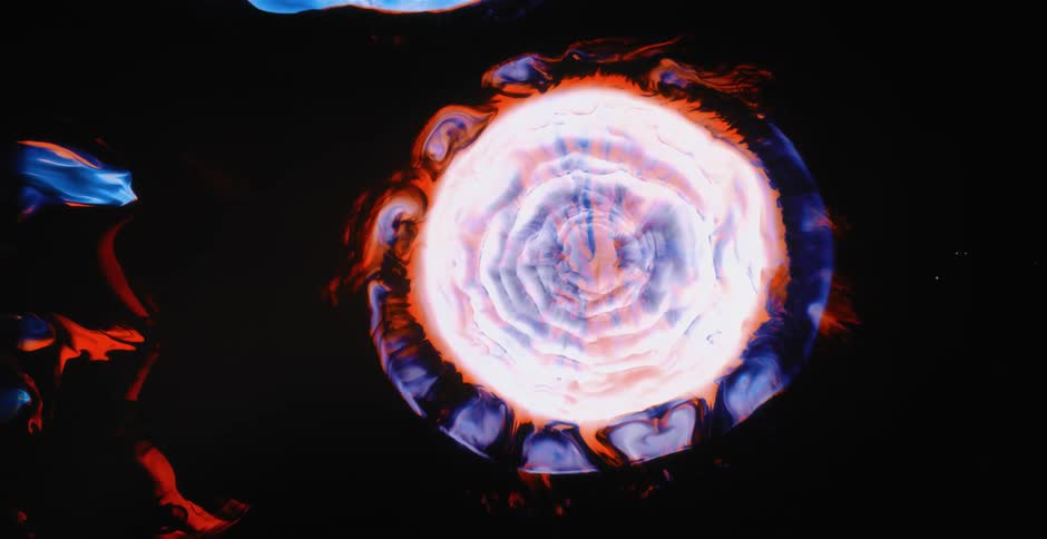 Colors flow leaving a pale glowing center against a black background