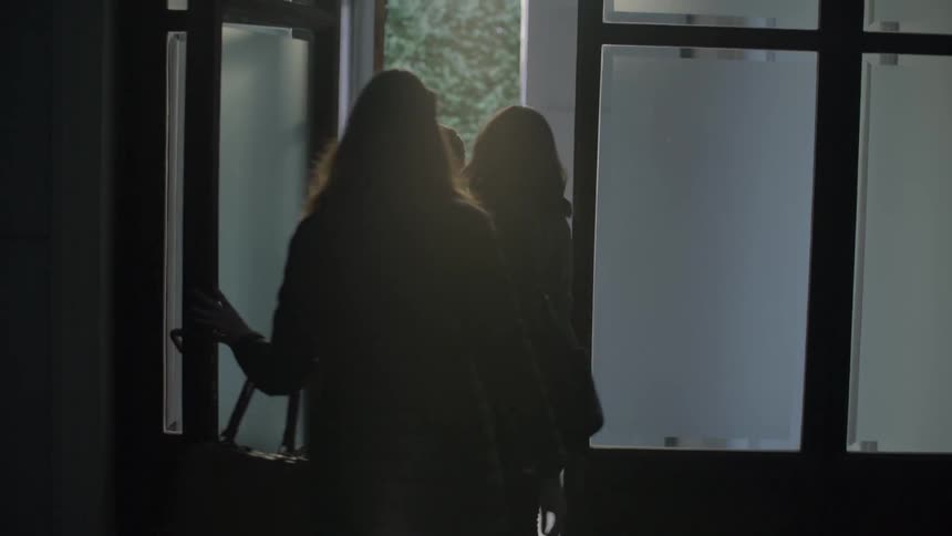Three women exit a building through a door