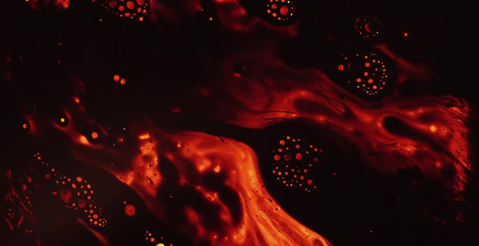 Red bubbles light up inside a molten red substance moving in the darkness as it glows