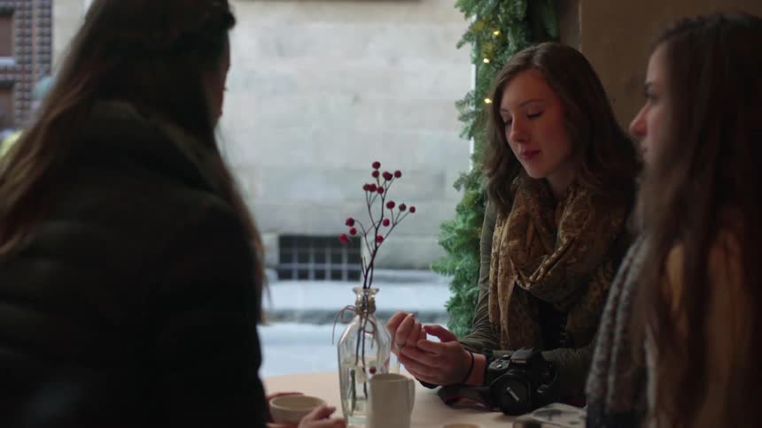 Three women sit at a patio table and talk