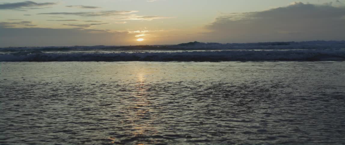 Water reflects sun sittingjust above as it flows toward shore