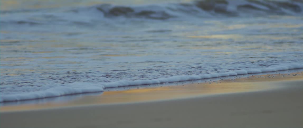 Small ocean waves gently wash up upon a sandy beach