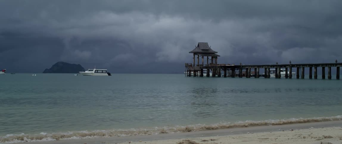 A boat stops in the ocean near a pier