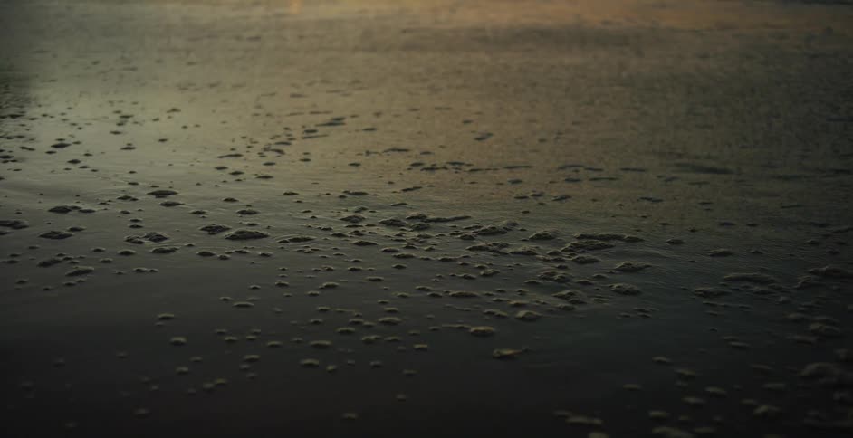 The tide washes out from a beach at sunset