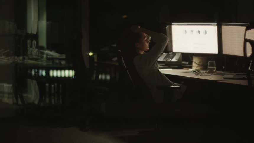 Distressed woman looking at monitor screens at night
