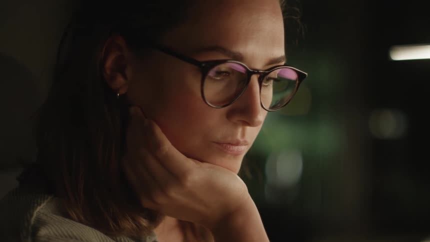 Glasses worn by woman reflect computer screen as she works