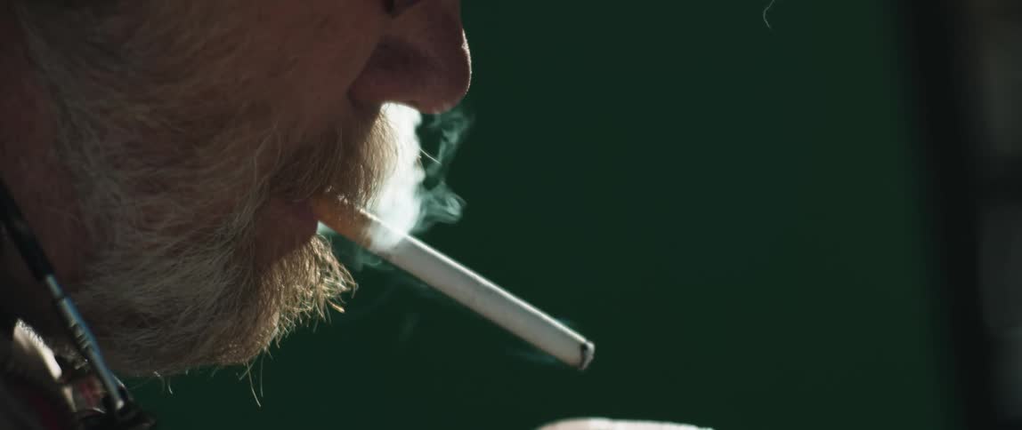 Bearded man lighting then smoking a cigarette