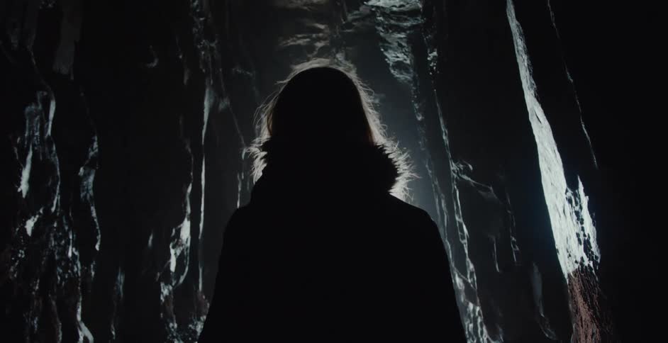 A woman looks up while exploring a cave