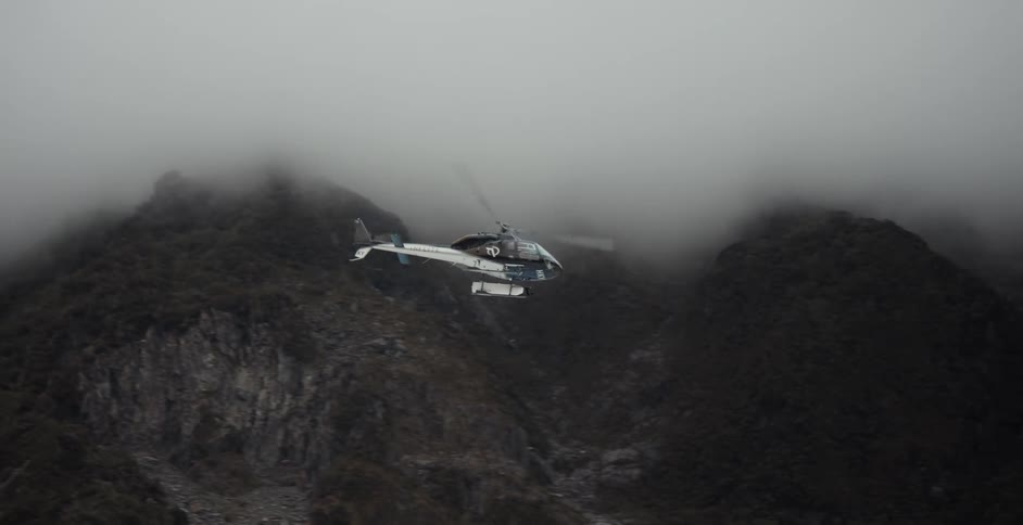 The helicopter flies over the mountains