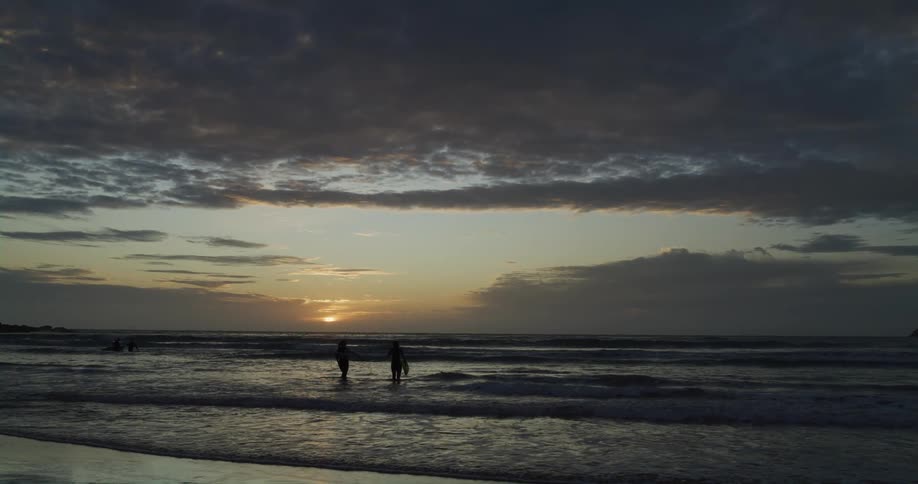 Surfers are on the beach looking at the water as waves roll in