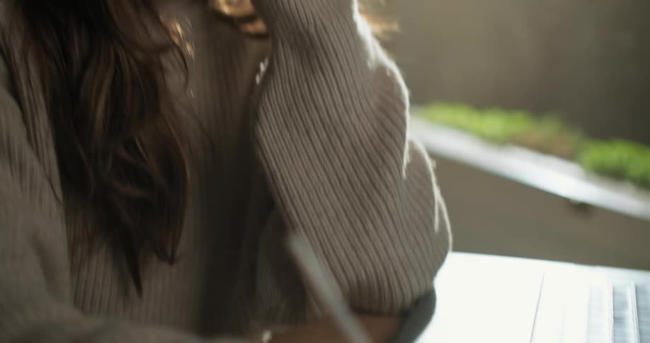A young woman talks on a smartphone in a cafe at sunrise