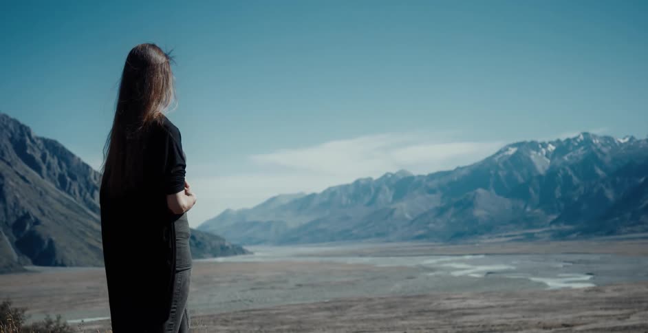 A young woman is standing in the middle of the wilderness