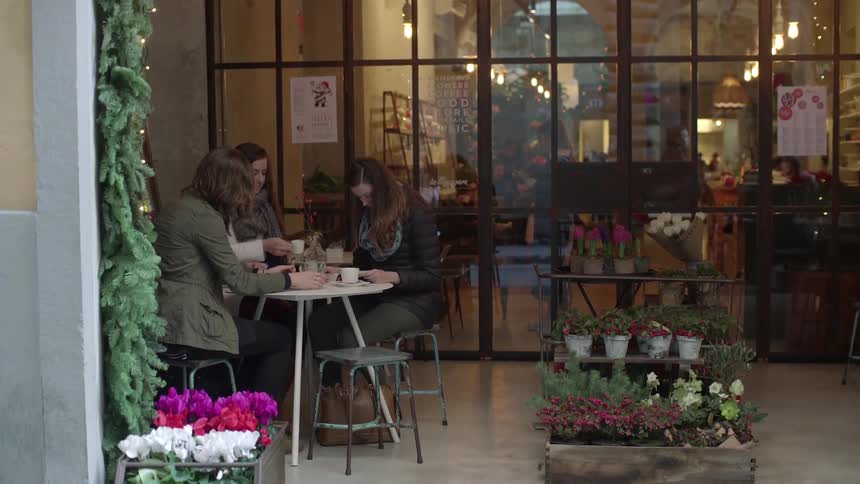 People sit down and drink and talk outside of a restaurant