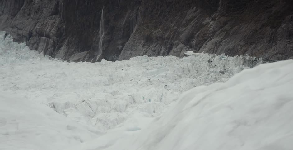 White helicopter flying over the rugged surface of a glacier in the mountains