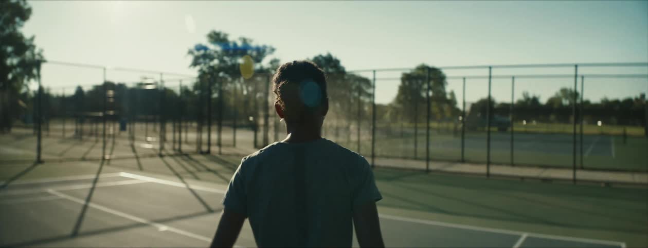 Young woman carrying a tennis racket jogs to her spot on the court at morning
